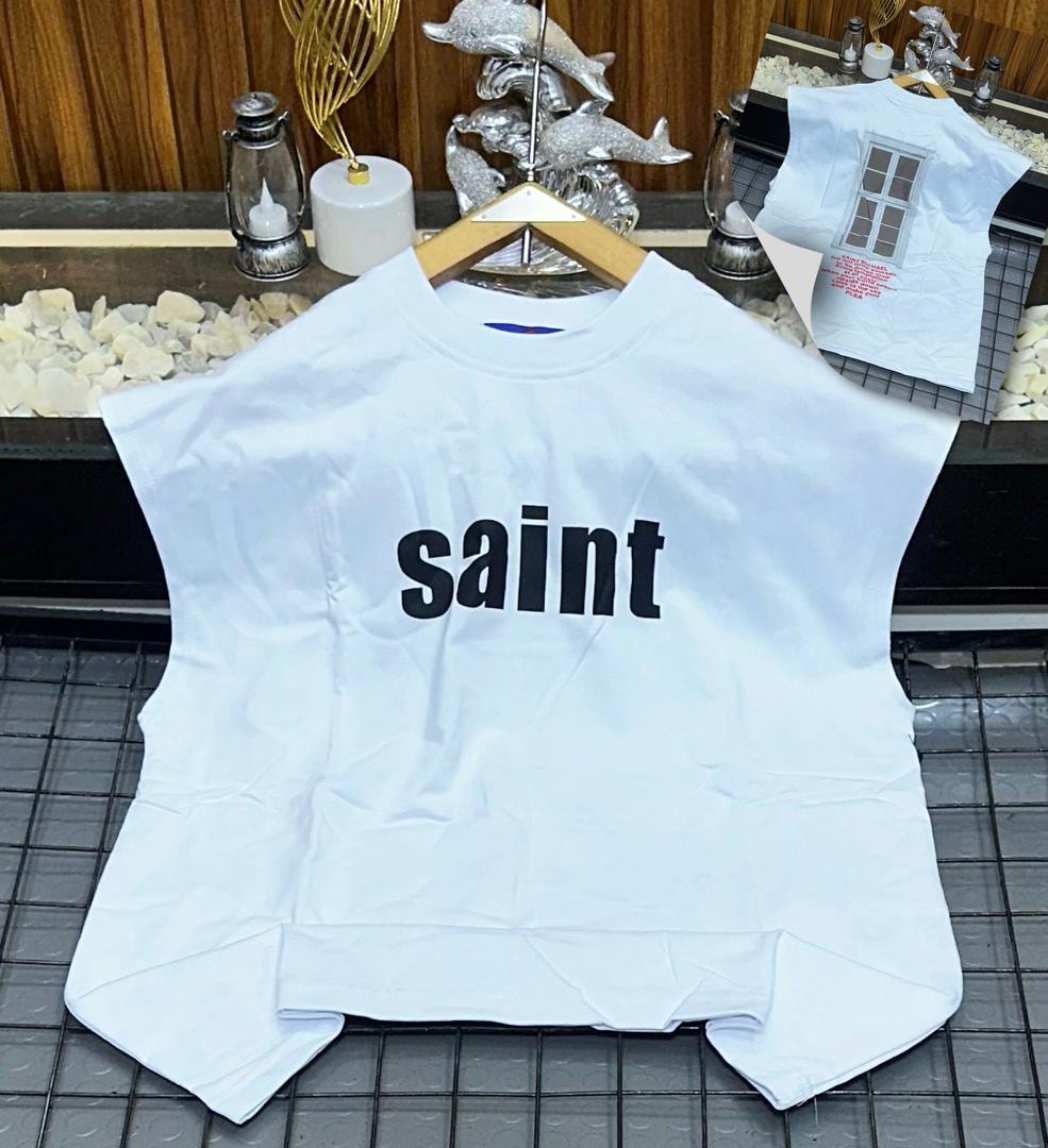 White oversized armless top with black saint text print on chest.