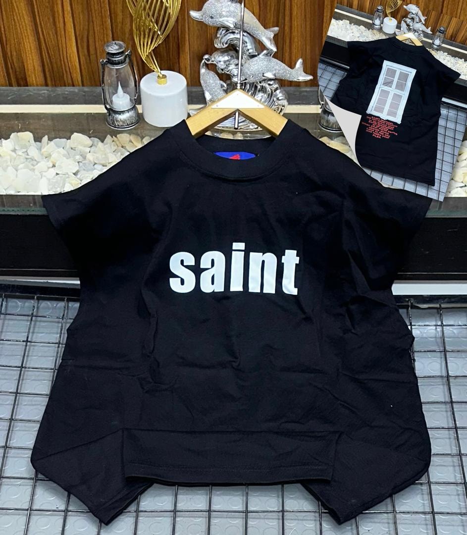 Black oversized armless top with white saint text print on chest.