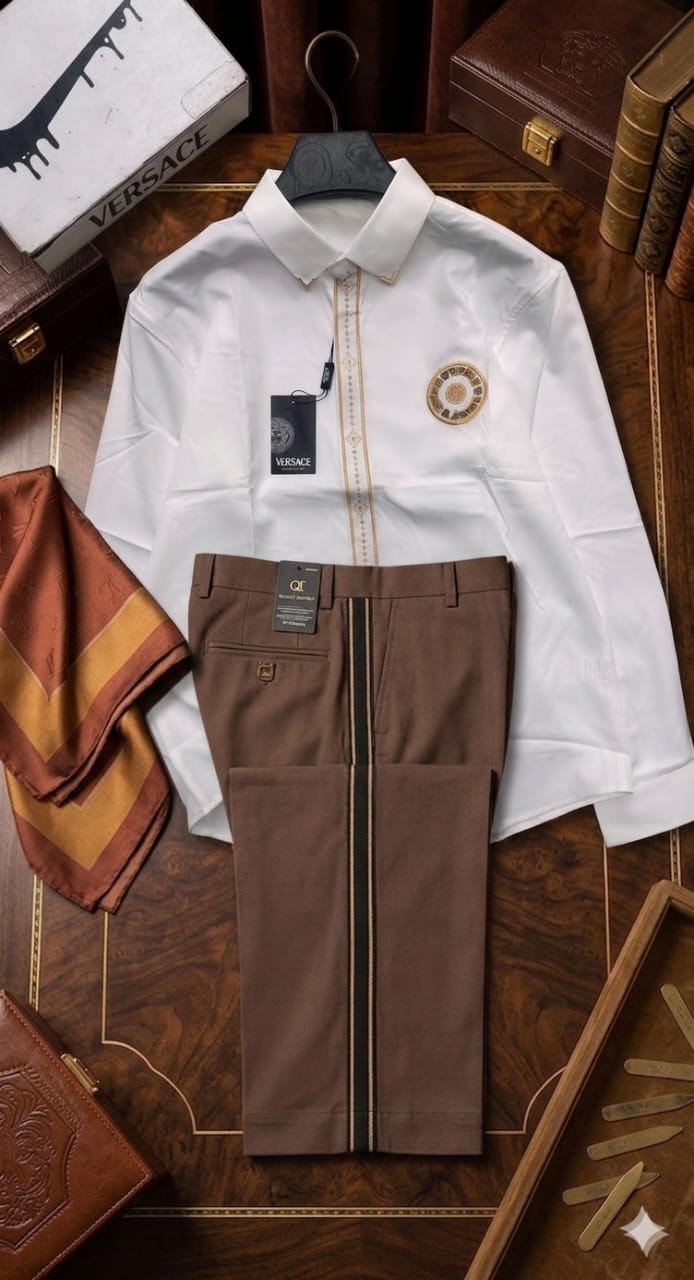 White Versace shirt with gold embroidery and brown trousers displayed with luxury branding items.
