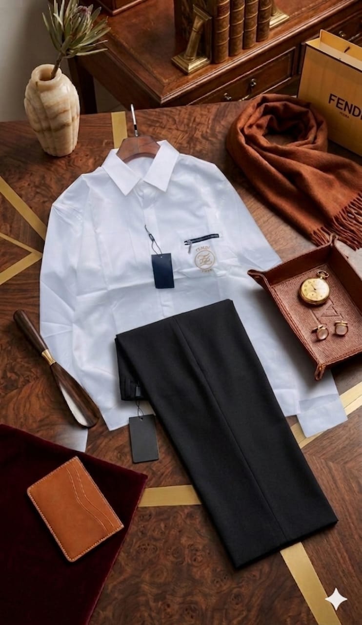 White Fendi shirt and black trousers styled on wooden table with luxury accessories and tags.