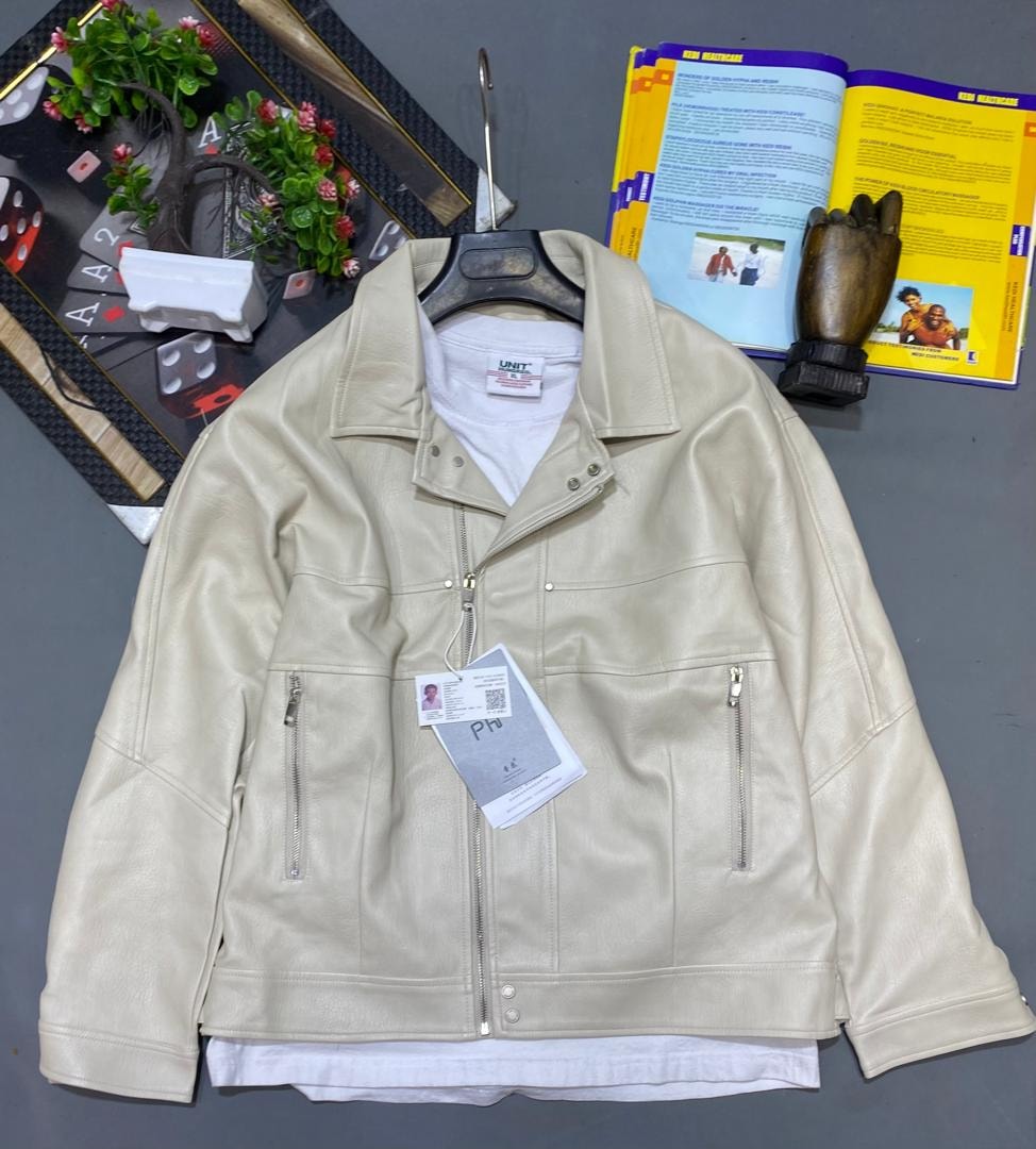 Cream leather biker jacket on hanger over white t-shirt with background accessories.