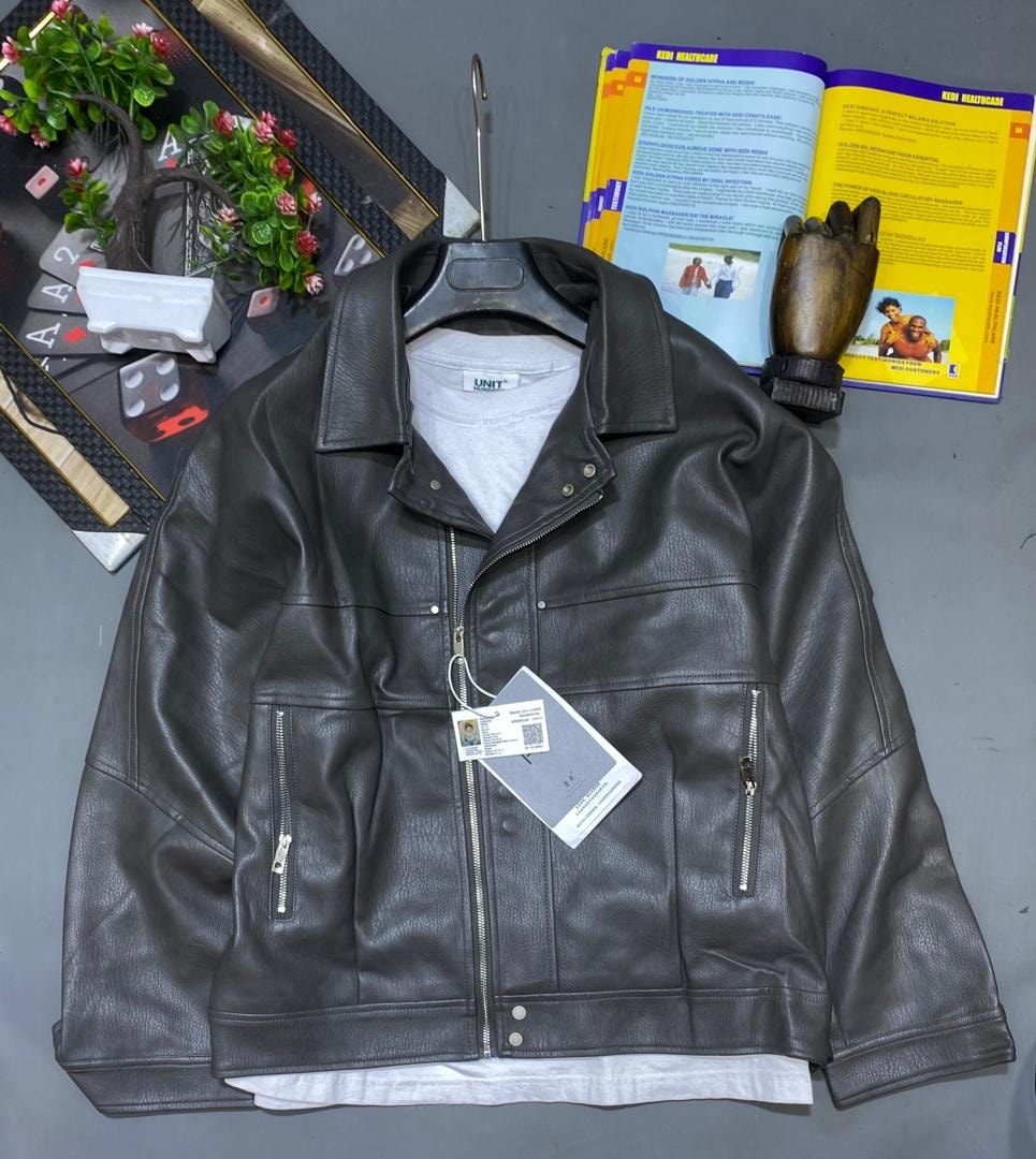 Black leather biker jacket on hanger over white t-shirt with background accessories.