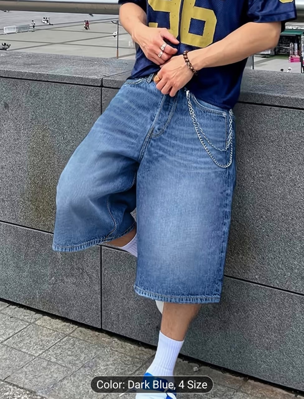 Model posing in dark blue chained 3/4 length denim shorts.