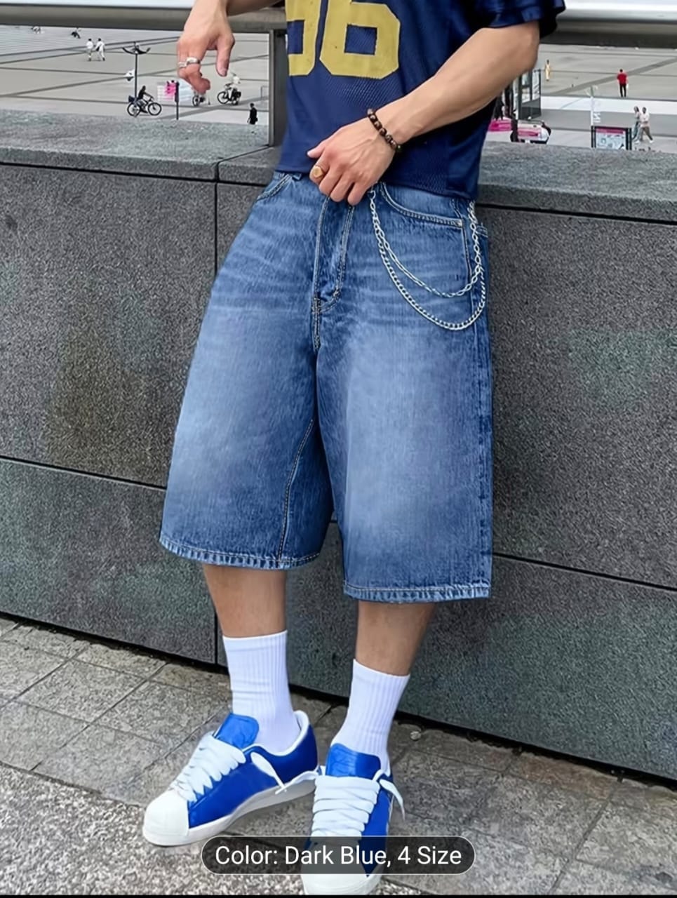 Model wearing dark blue 3/4 denim shorts with chain accessory.