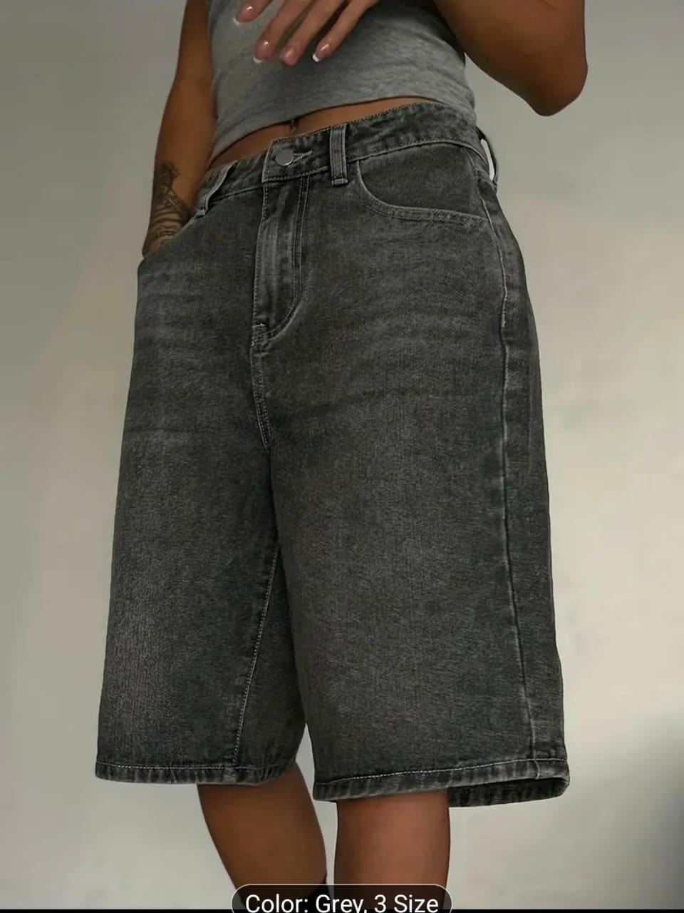 Side view of model in gray 3/4 length jean shorts.