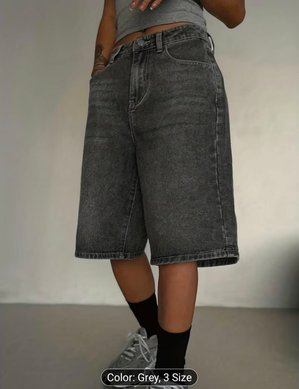 Model wearing gray washed 3/4 length denim shorts.