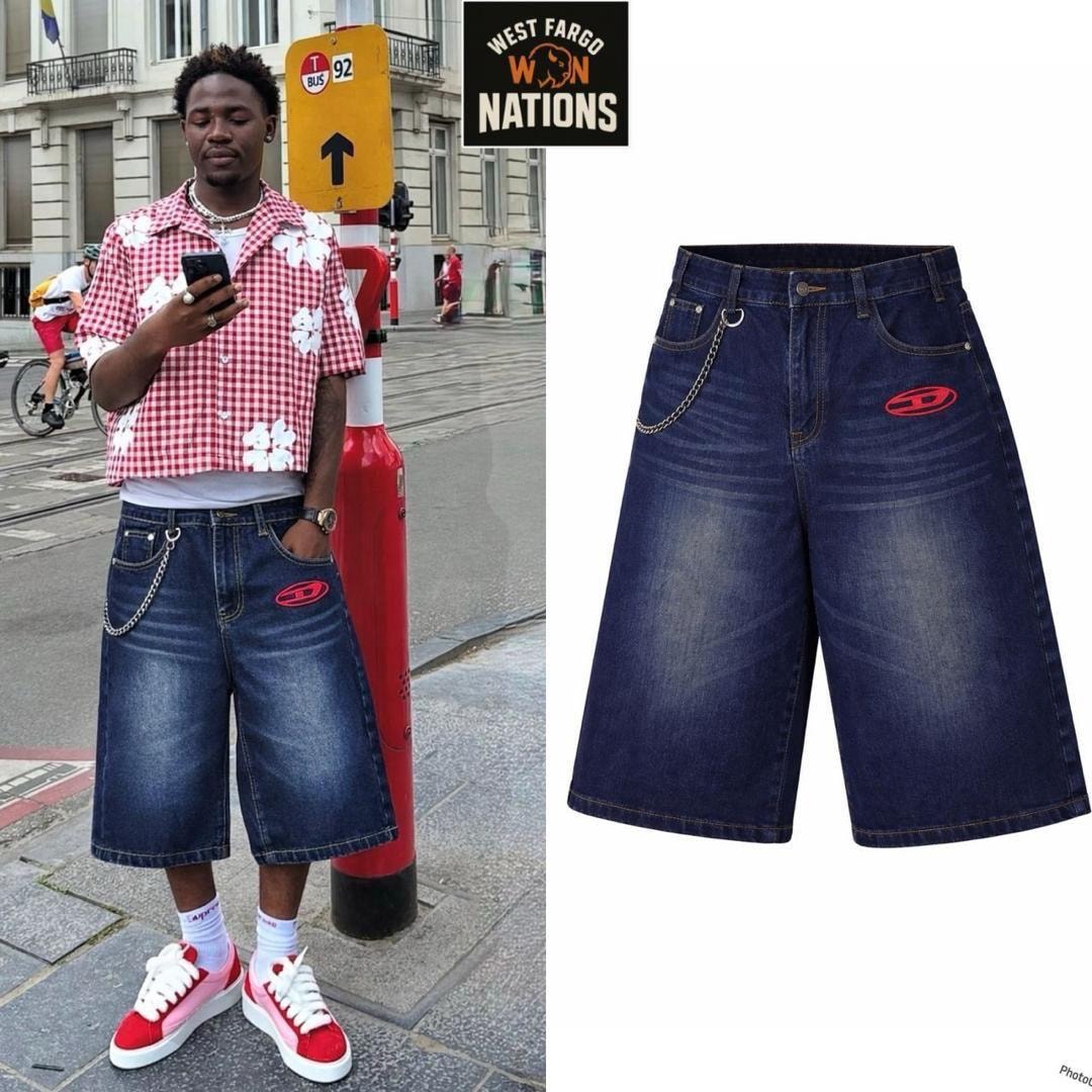 Model wearing navy denim 3/4 jorts with chain and red logo detail on urban street.