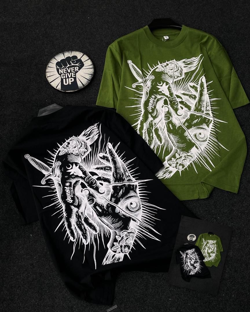 Black and green t-shirts featuring white intricate spiked heart and eye design.