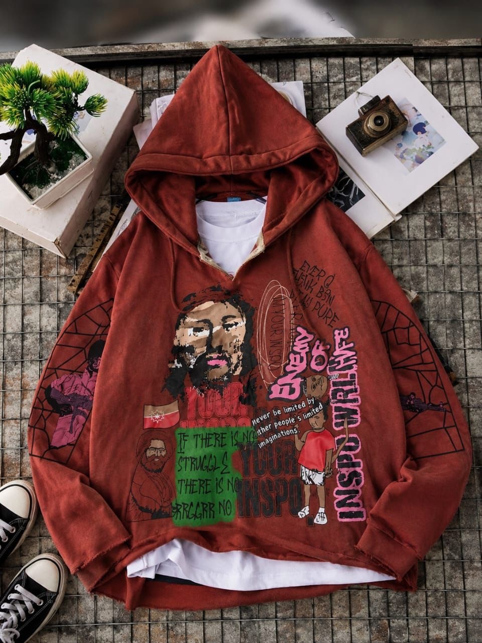 Rust brown oversized hoodie with multiple inspirational graphics, text prints, and portraits in flat lay.