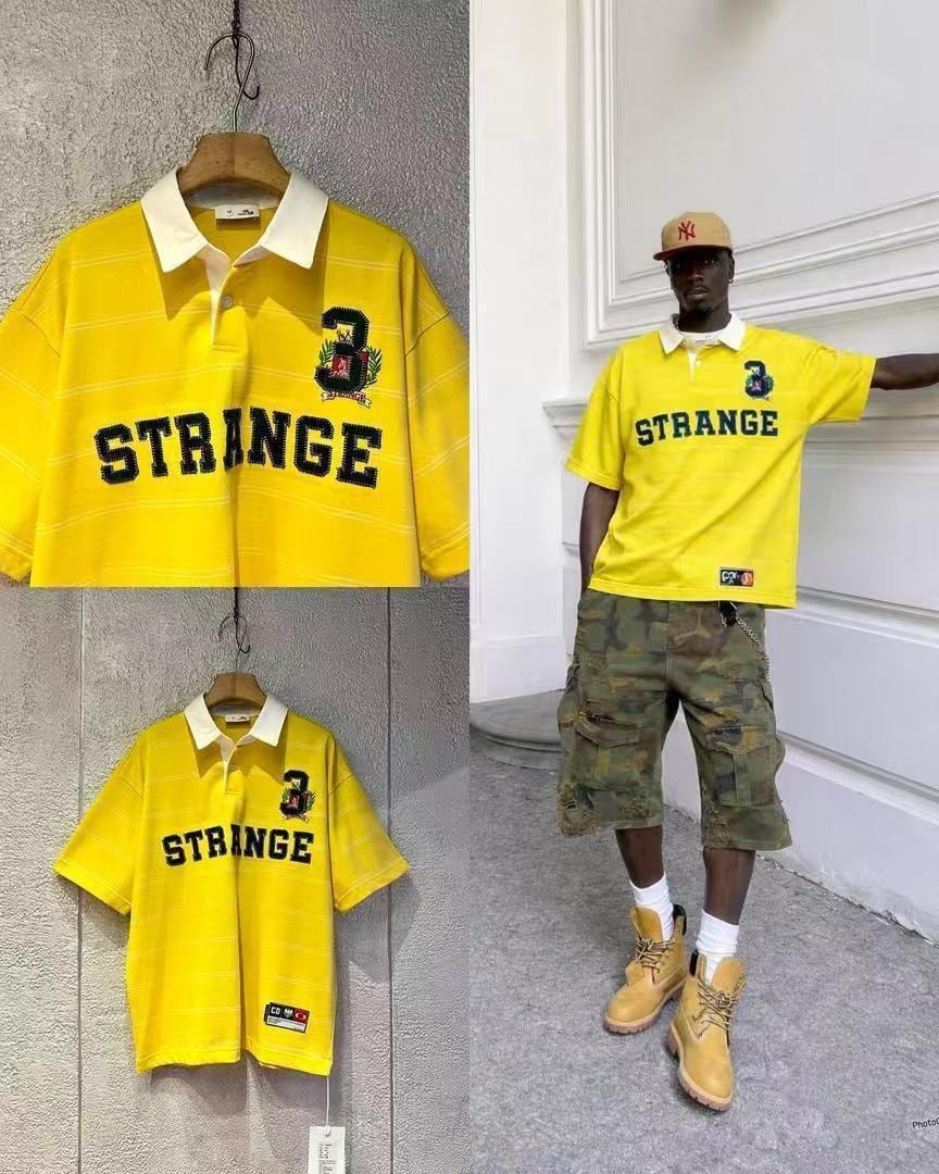 Yellow striped polo shirt with black STRANGE graphic on hanger and worn by model.