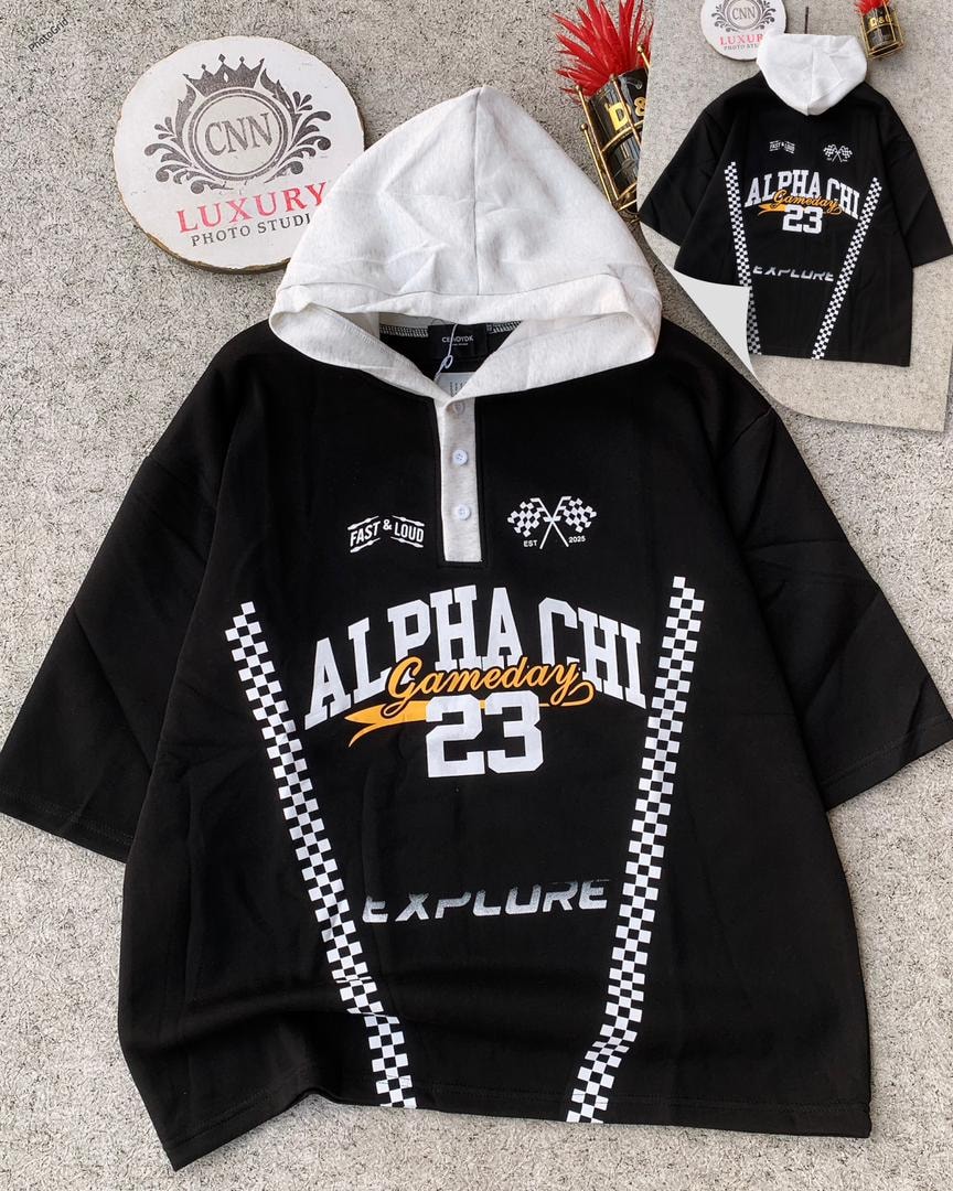 Black oversized hooded top with white hood, button placket, and contrasting ALPHA CHI 23 graphics with checkered patterns.