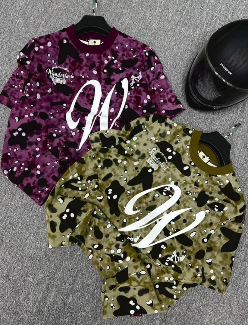 Purple and green camo pattern t-shirts with oversized white script W beside black helmet.
