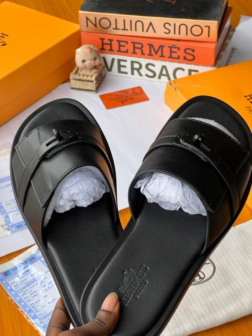 Close-up top view of black Hermès H buckle slides held in hand showing insole.