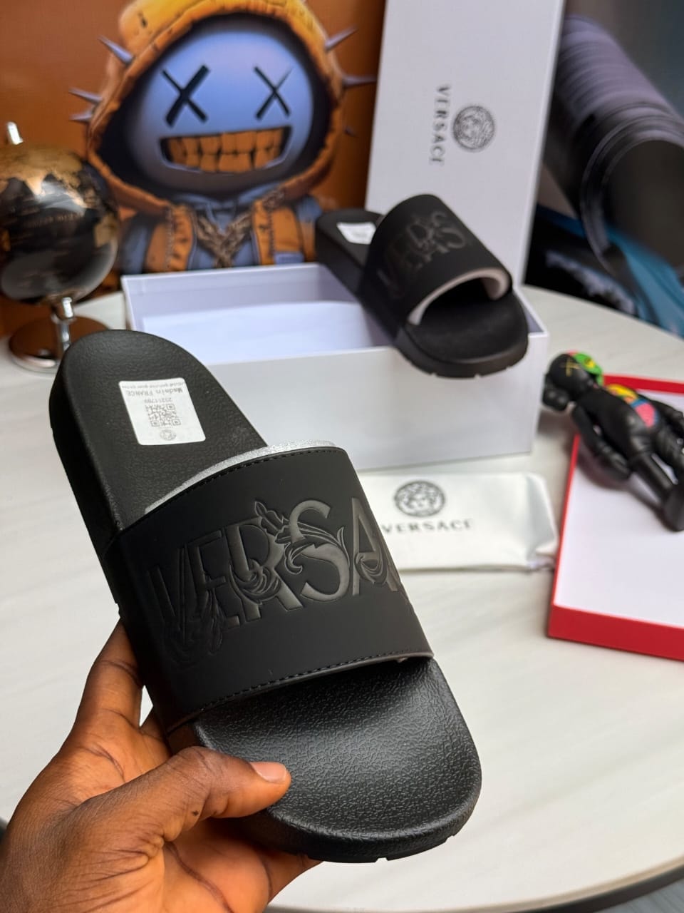 Black Versace slides with embossed VERSACE text and decorative pattern.