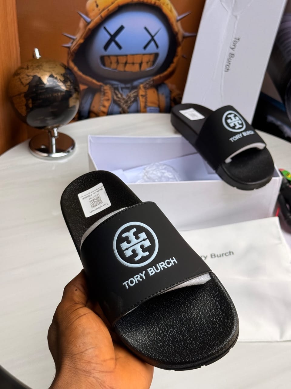 Black Tory Burch slides with circular logo and brand name on strap.