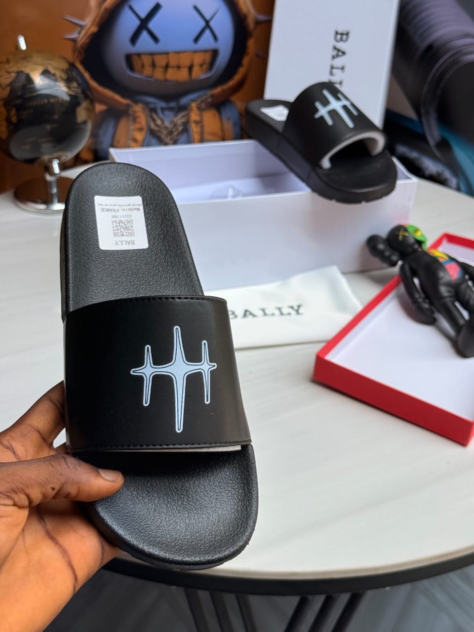 Black Bally slides featuring light blue geometric logo on strap.