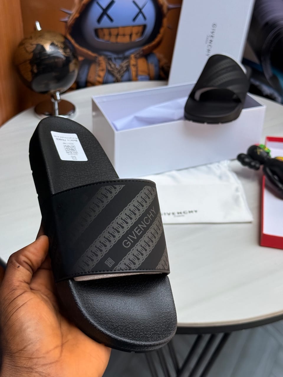 Black Givenchy slides with striped pattern and logo on wide strap.