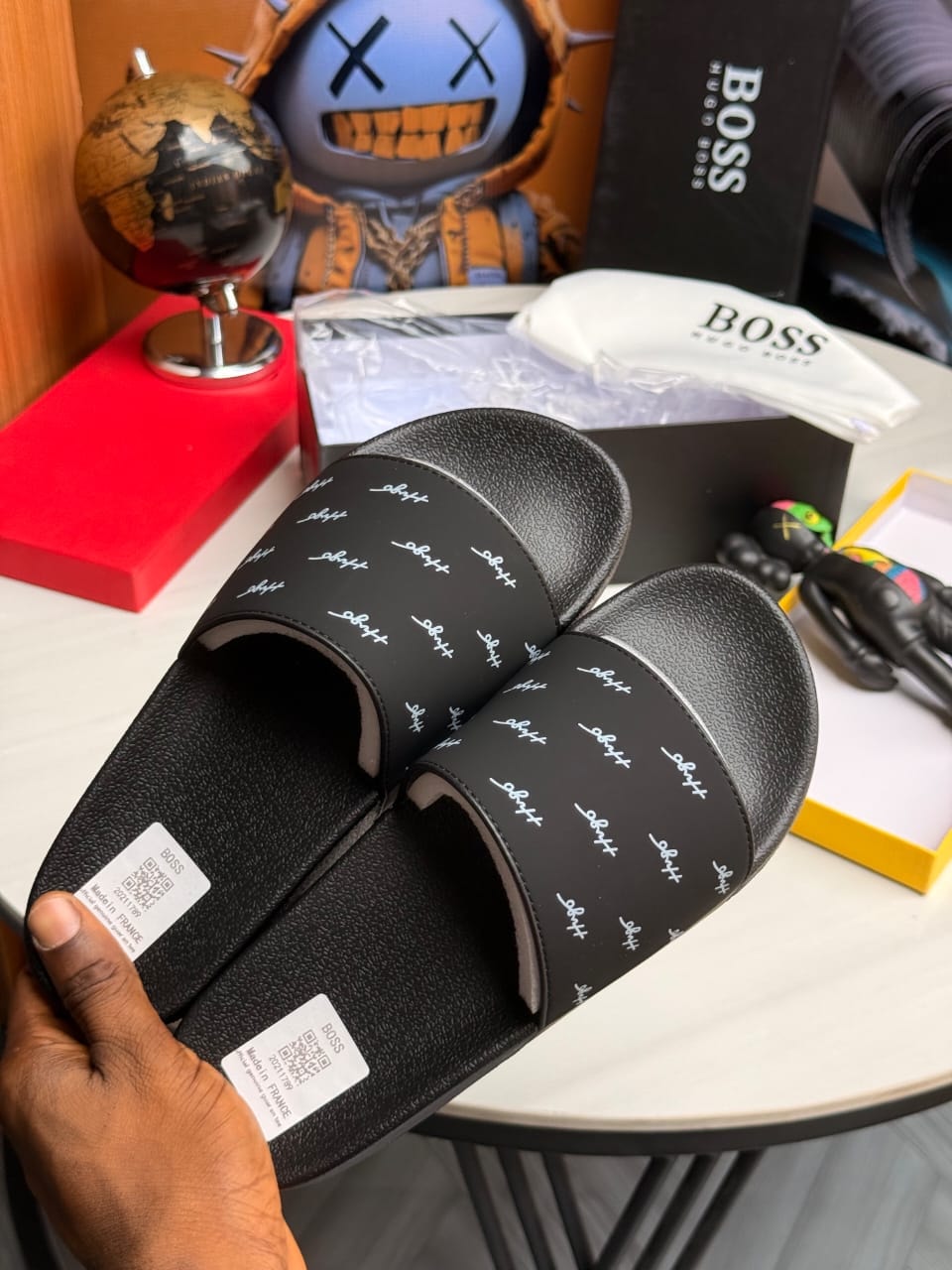 Black BOSS slides with repeating white script logo pattern.