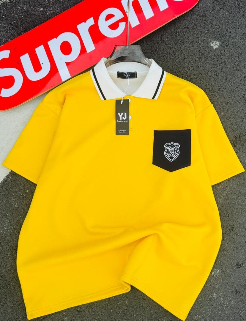 Yellow polo shirt with white contrast collar and black pocket with shield embroidery.