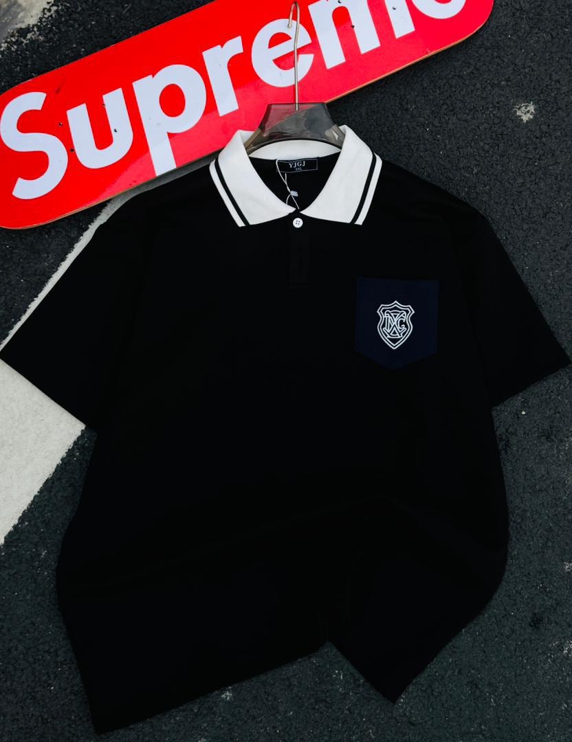 Black polo shirt with white contrast collar and shield embroidery on chest pocket.