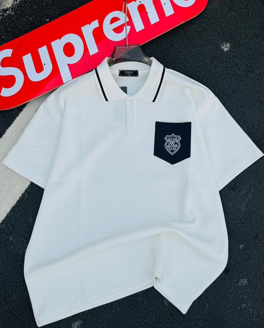 White polo shirt with black contrast collar and shield embroidery on chest pocket.