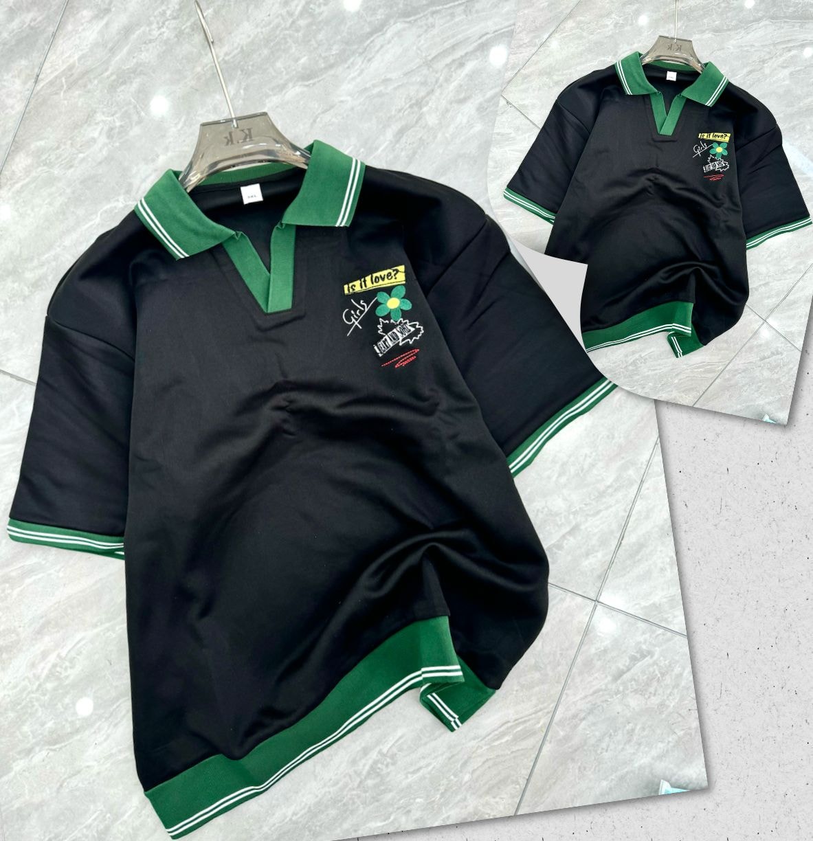 Black polo shirt with green trim and chest embroidery on hanger and flat lay.