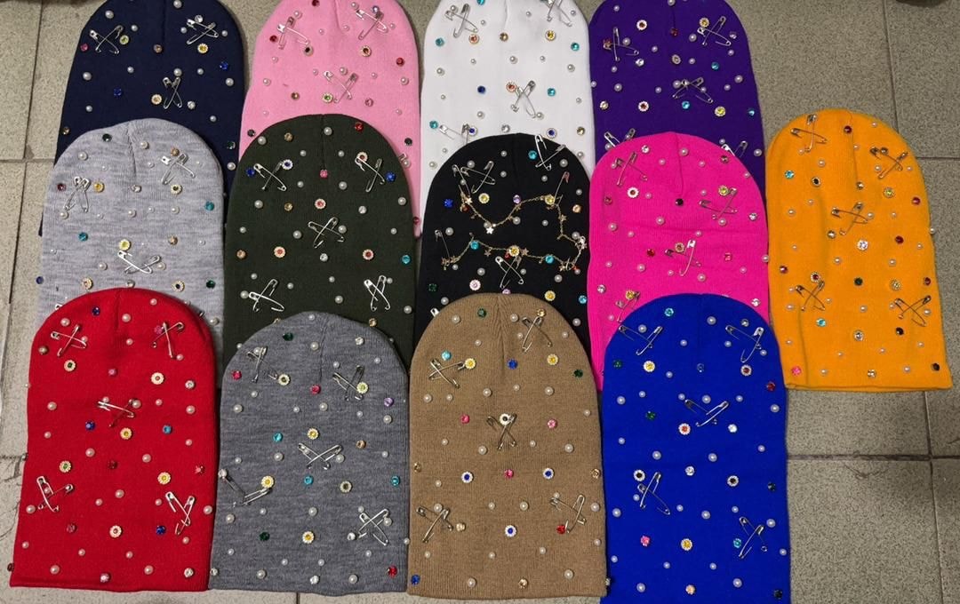 Assortment of rhinestone embellished beanies in over 10 colors including navy, pink, white, purple, red, blue and gray.