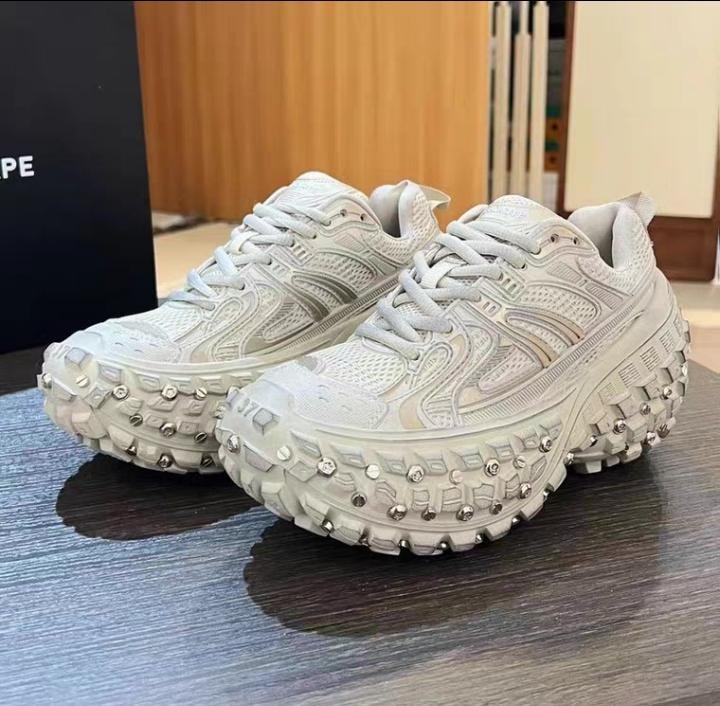 White studded chunky sneakers displayed on wooden surface.