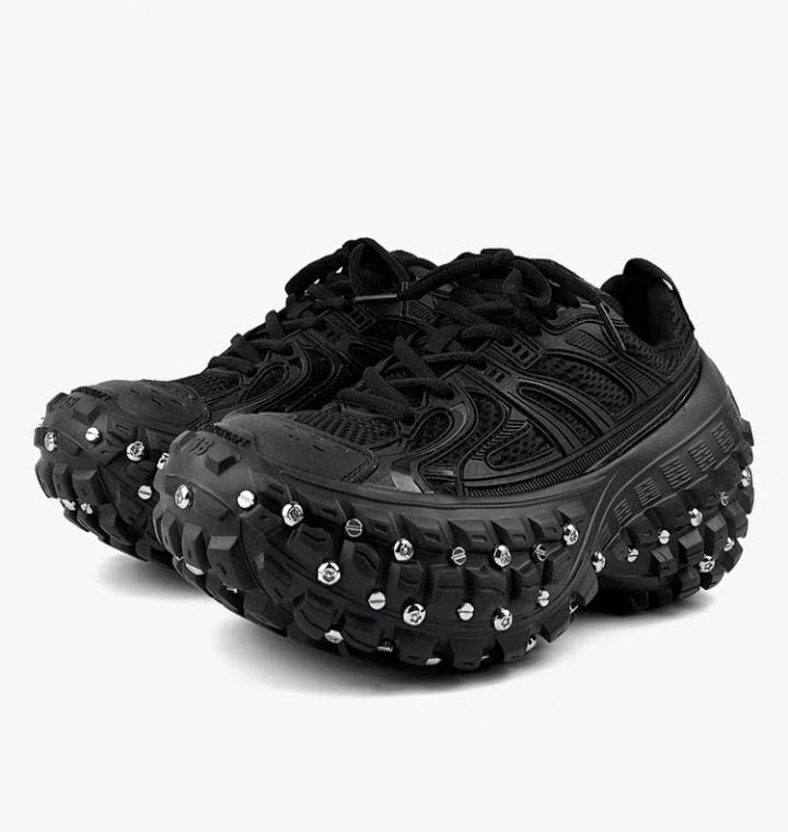 Pair of black chunky sneakers with metal studs on white background.