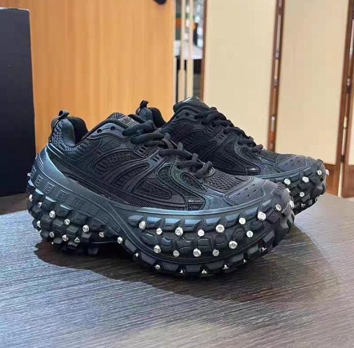 Black studded chunky sneakers displayed on wooden table.