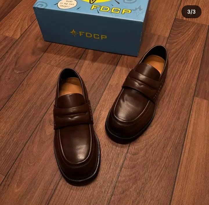 Brown leather FDCP loafers on wooden floor with brand box.
