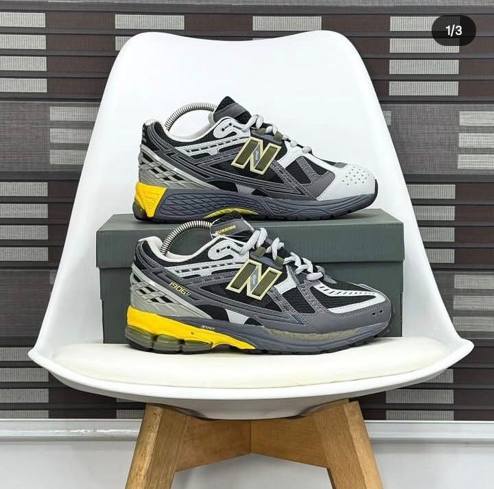 New Balance 1906U sneakers in black grey and yellow colorway displayed on white chair and shoebox