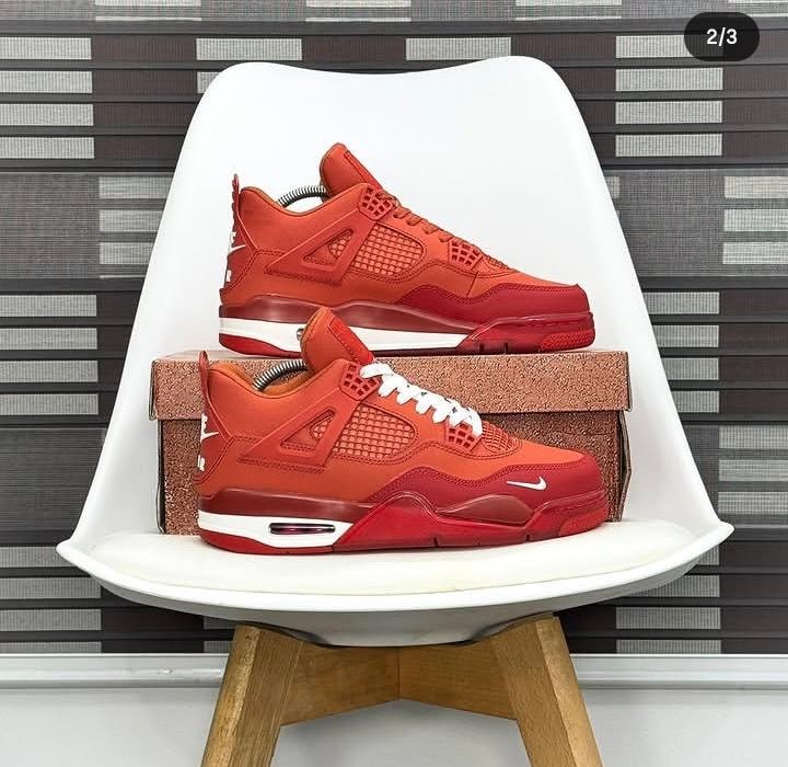 Red Air Jordan 4 sneakers displayed on white chair and box.