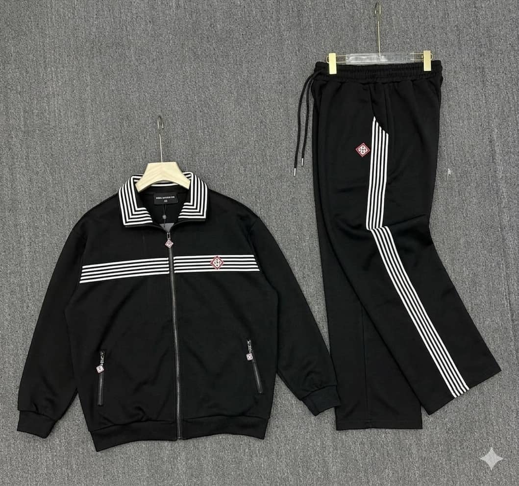 Black tracksuit set displayed on hangers with striped details on jacket and pants.