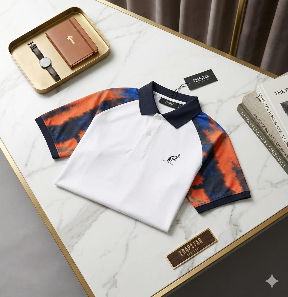 White Trapstar polo with navy collar, tie-dye sleeves and kangaroo logo on marble table.