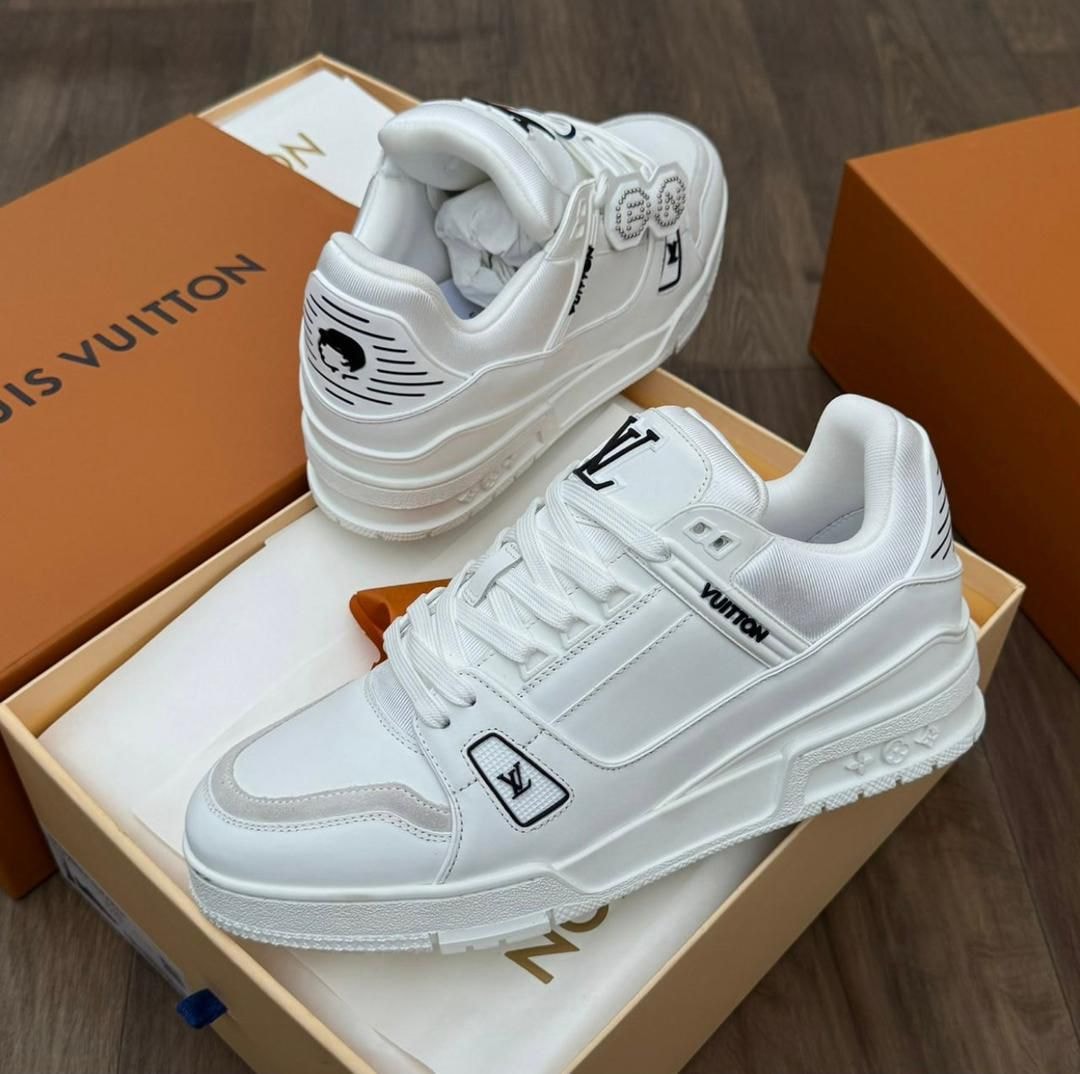 White Louis Vuitton sneaker displayed in orange branded box, showing side and heel views.