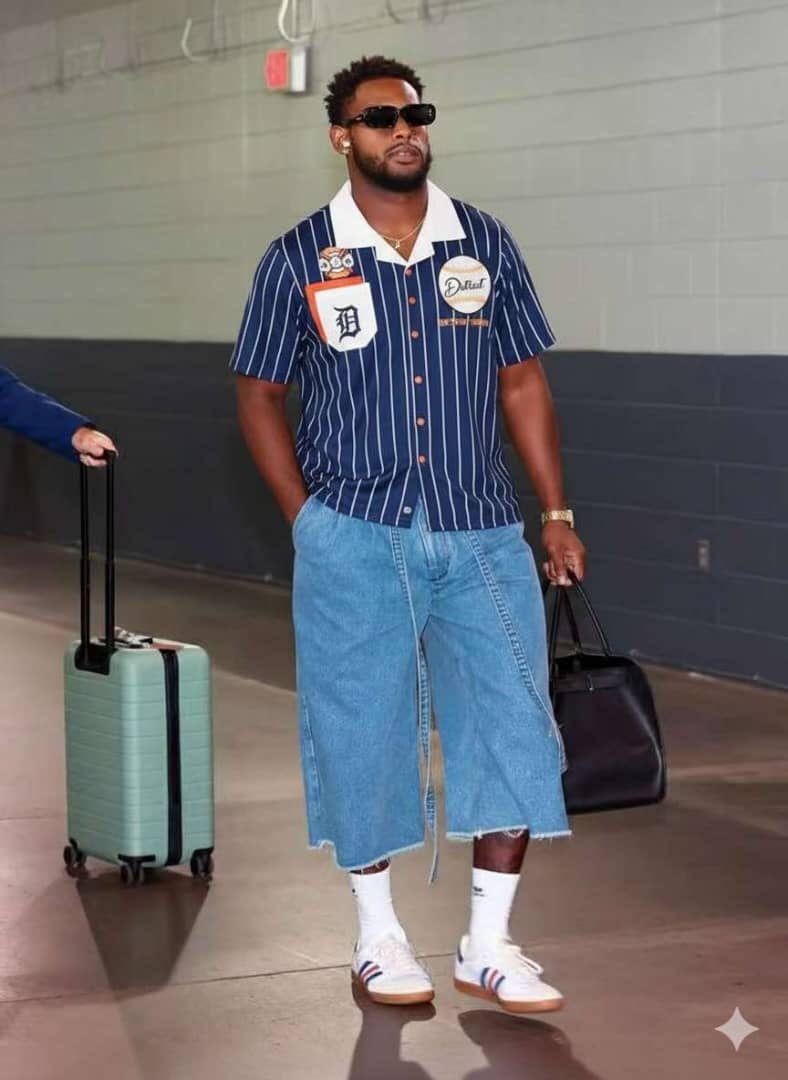 Man wearing blue striped short sleeve shirt with white collar, Detroit patches and button front, styled with denim shorts.