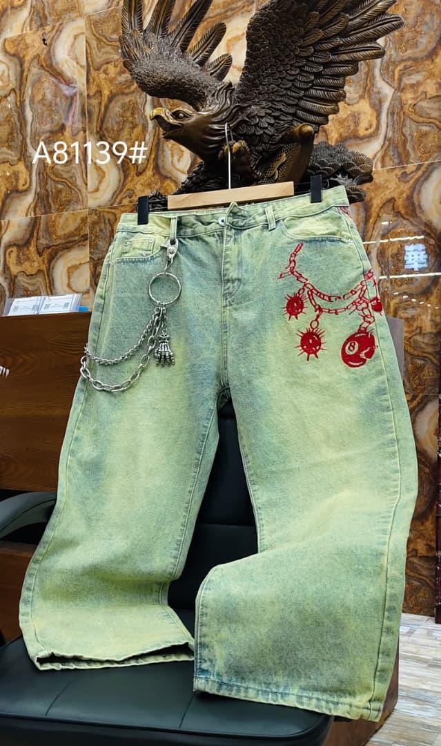 Front view of light green baggy jeans featuring red chain and bomb designs with attached accessories.