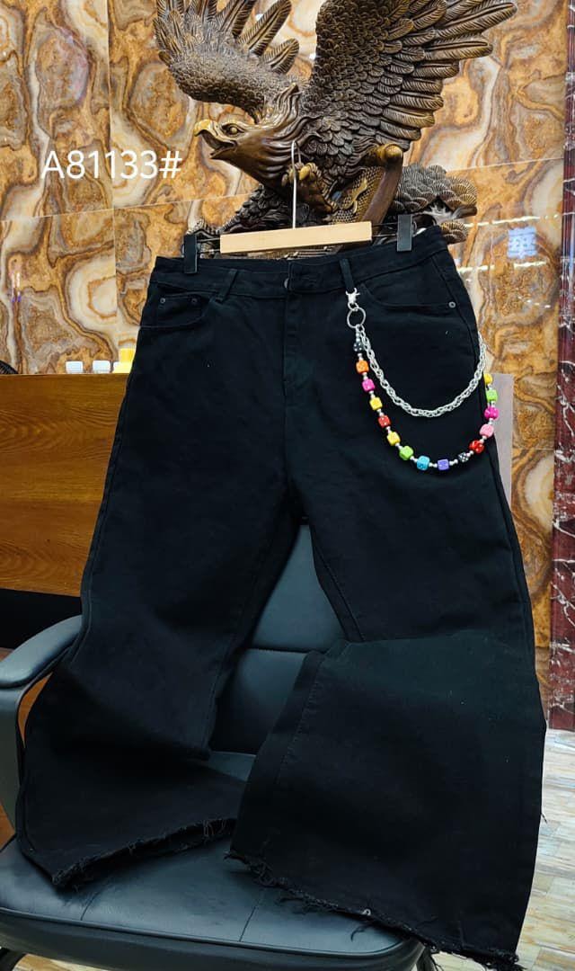 Black baggy jeans with multicolored beaded chain accessory and metal details on display.