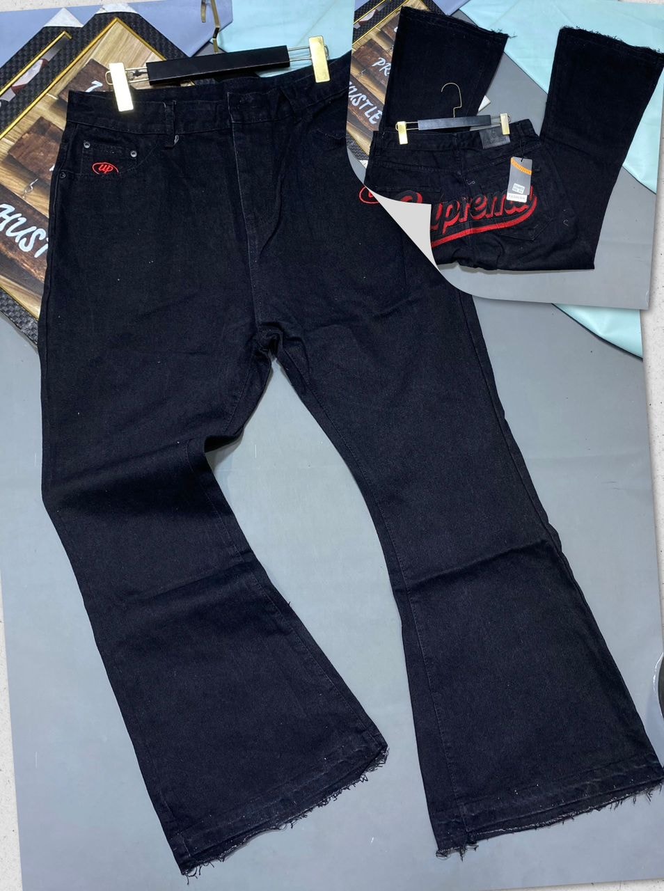 Black baggy jeans with red logo embroidery on back pocket, shown in front and back views with flared legs.