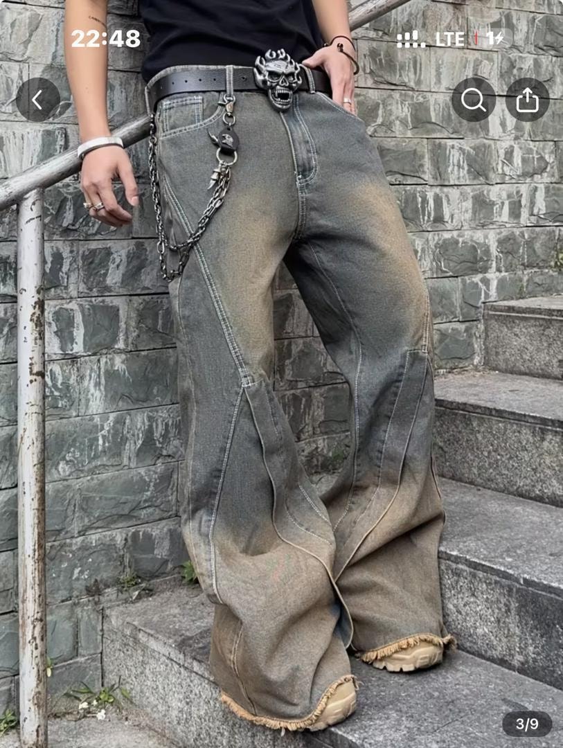 Model in gray baggy jeans with chain accessory, skull belt and urban background.