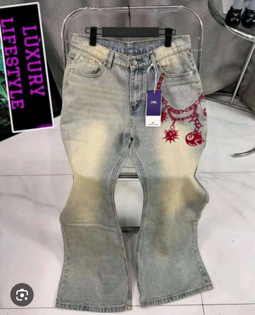Light blue faded baggy jeans with red chain and skull design on pocket area displayed on stand.