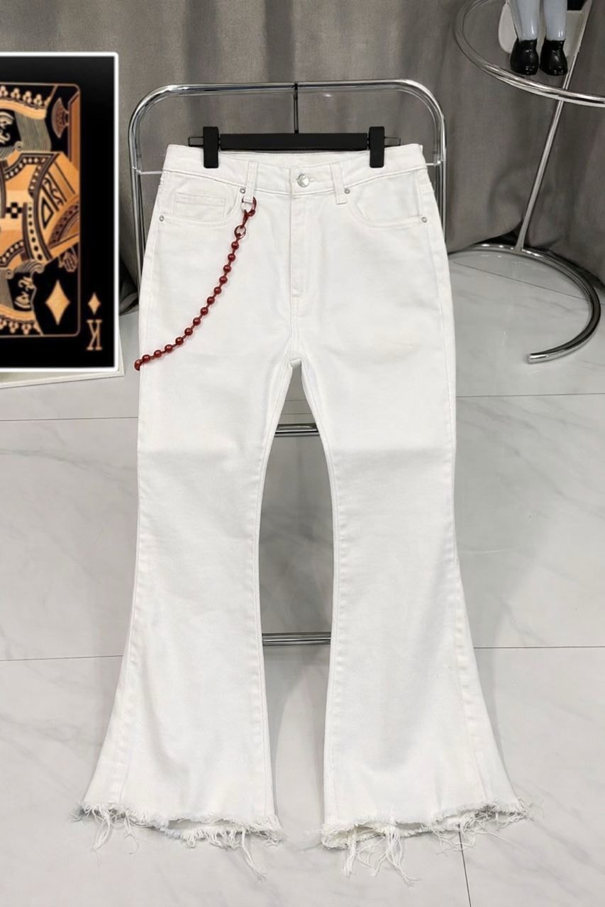 White flared baggy jeans with frayed hems and red beaded chain displayed on a stand.