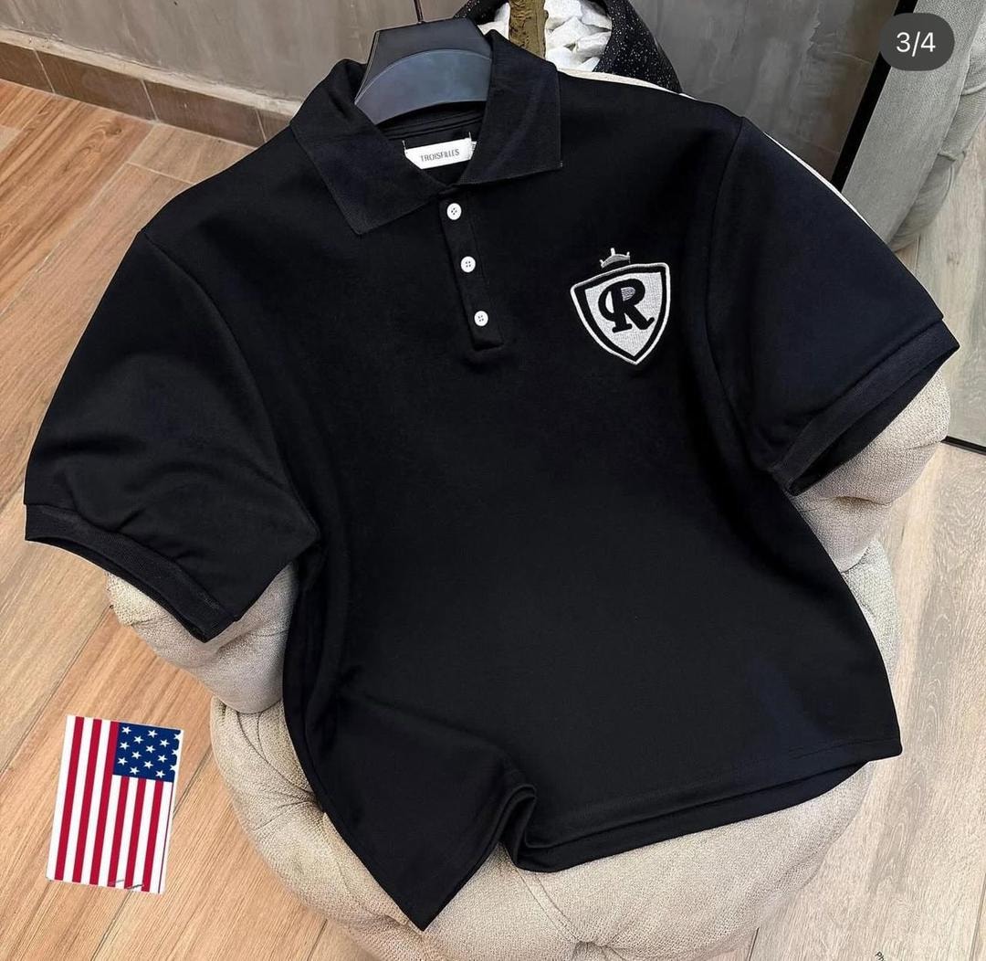 Black polo shirt with white shield crest R logo on the chest.