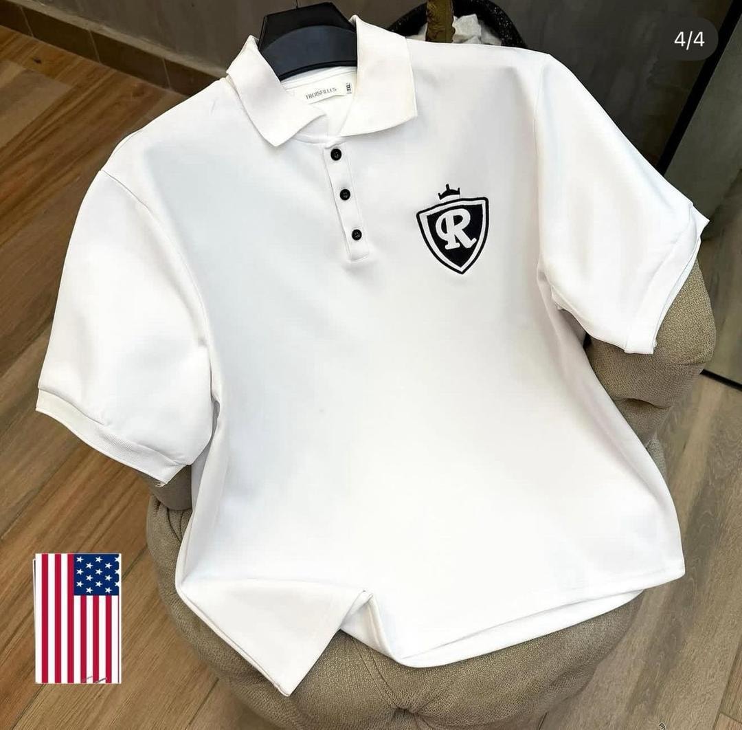 White polo shirt with black shield crest R logo on the chest.