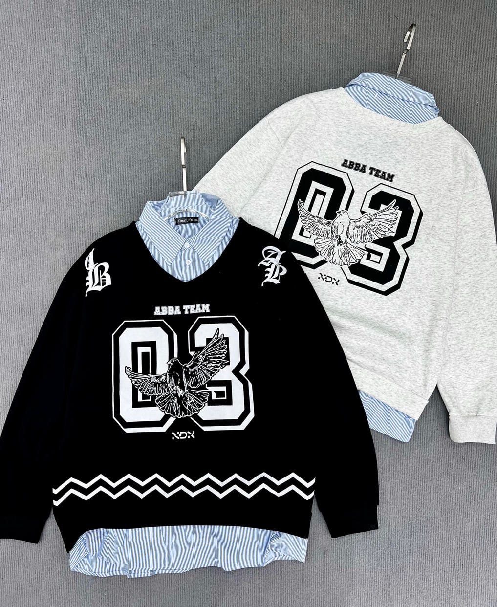 Black and gray sweatshirts with ABBA TEAM 03 eagle graphics, layered over striped collared shirts.