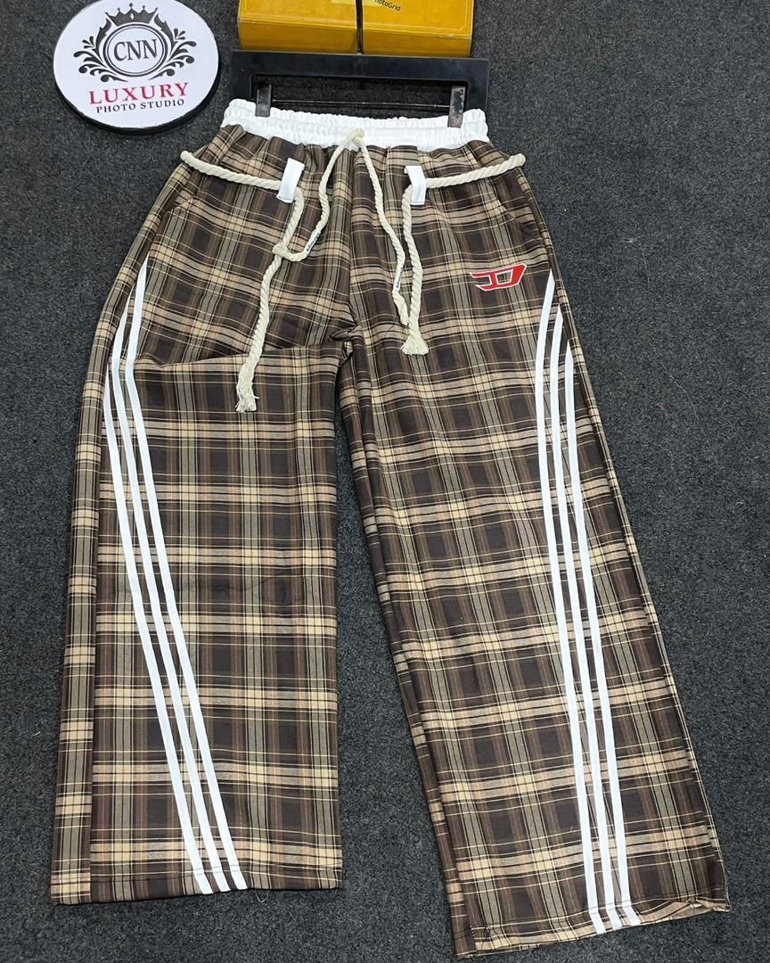 Brown plaid joggers laid flat showing white stripes, drawstring and elastic waist.