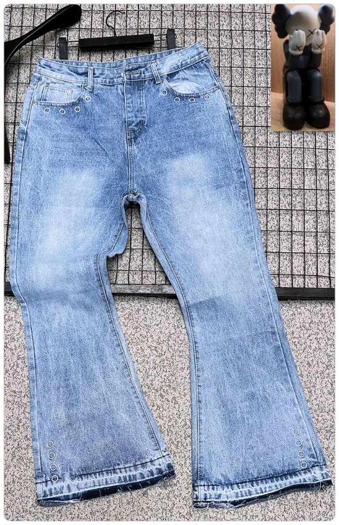 Light blue baggy jeans with silver eyelets along legs and waist, shown flat on grid with figurine inset.