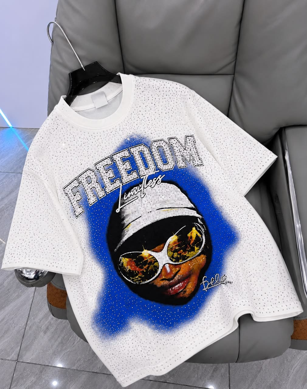 White rhinestone graphic t-shirt with FREEDOM portrait design on hanger.