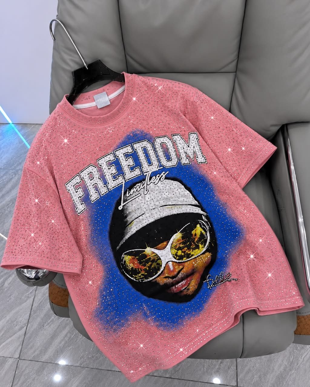 Pink rhinestone graphic t-shirt with FREEDOM portrait design on hanger.